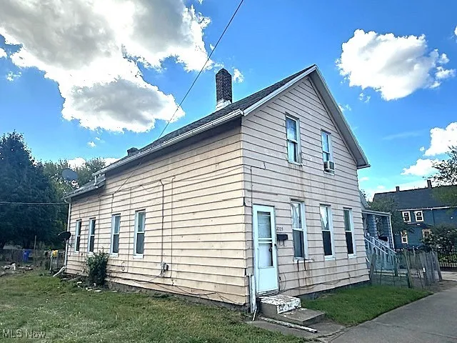 View of side of home featuring a lawn and a chimney