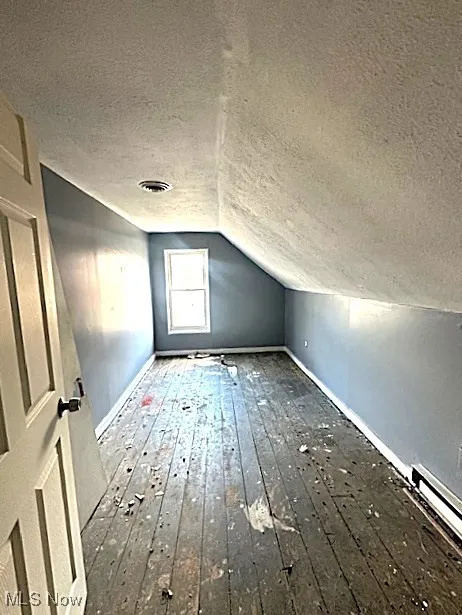 Bonus room featuring a textured ceiling, hardwood / wood-style floors, lofted ceiling, and baseboard heating