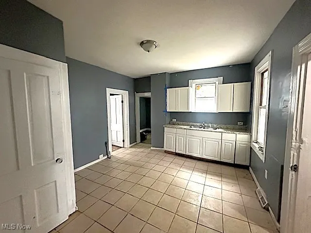 Kitchen with light tile patterned flooring, white cabinets, and light countertops