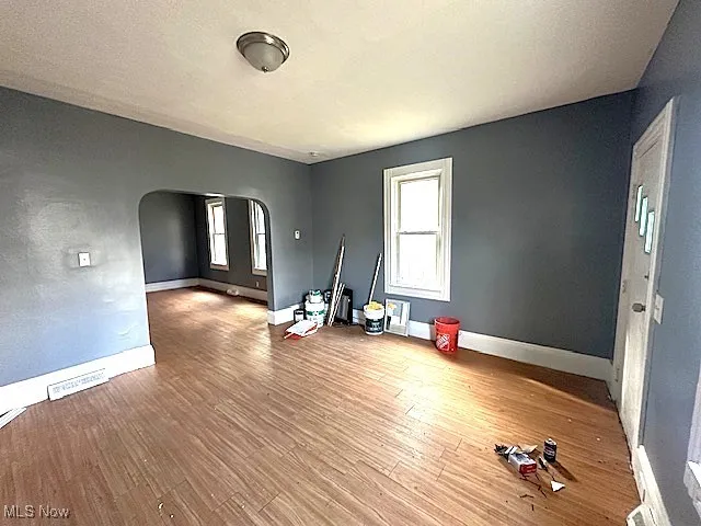 Spare room featuring arched walkways and light wood-type flooring