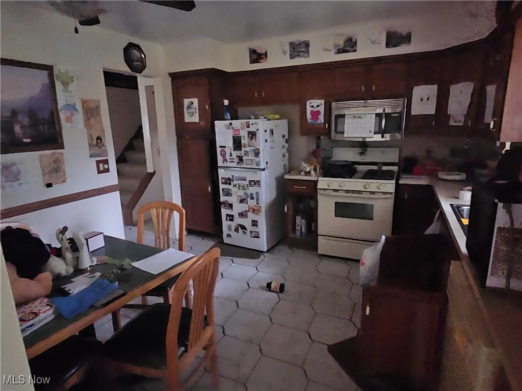 Kitchen with white appliances, light countertops, and a ceiling fan