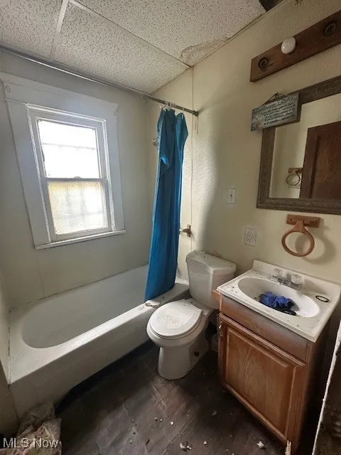Full bathroom with dark wood-style flooring, vanity, shower / bath combination with curtain, and a paneled ceiling