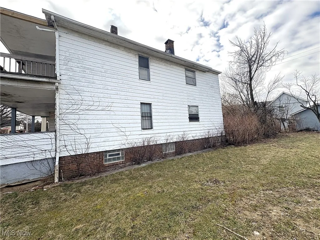 View of home's exterior featuring a lawn and a chimney