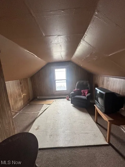 Bonus room featuring wooden walls, carpet floors, lofted ceiling, and baseboard heating