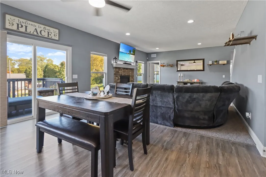 Dining room featuring a fireplace, wood finished floors, recessed lighting, a textured ceiling, and ceiling fan