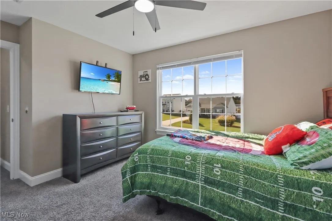 Carpeted bedroom featuring a ceiling fan and baseboards