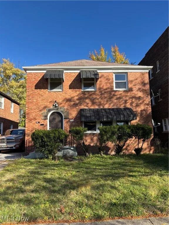 View of front of house with brick siding and a front lawn