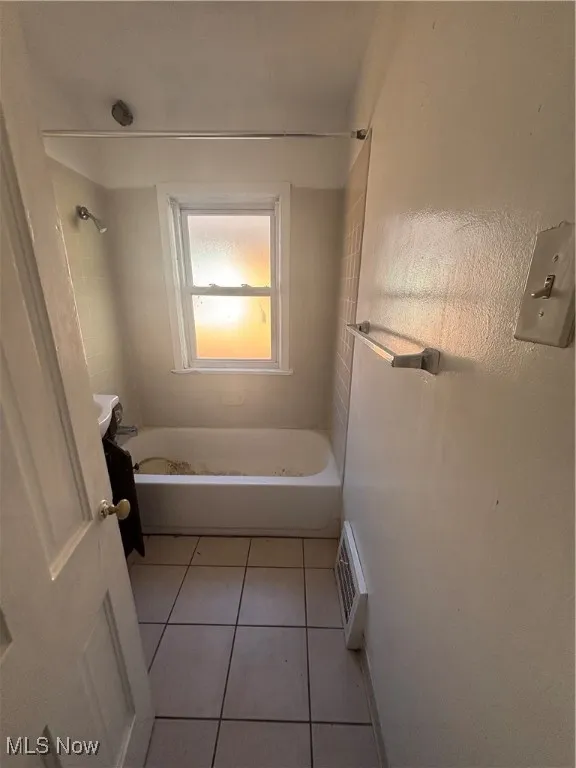 Bathroom with light tile patterned floors and shower / washtub combination