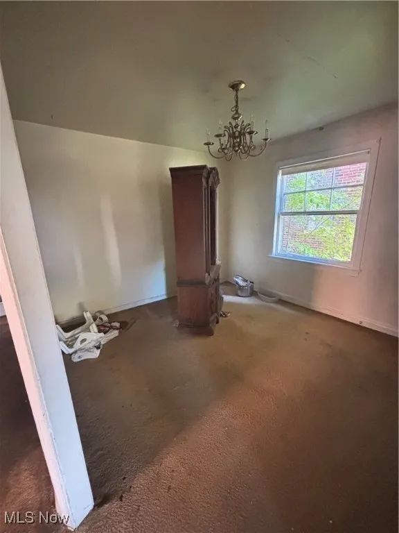 Unfurnished dining area featuring a chandelier and carpet floors