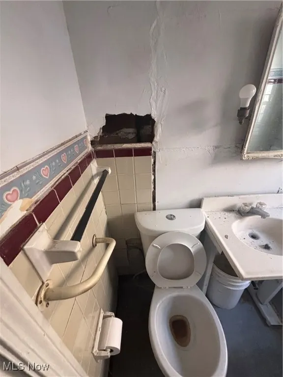 Half bath with tile walls and a wainscoted wall