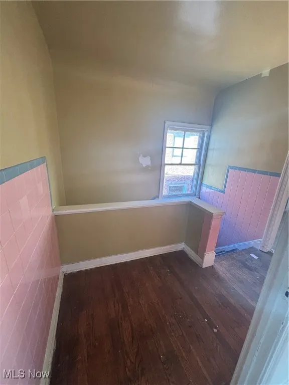 Spare room featuring dark wood-style floors and wainscoting