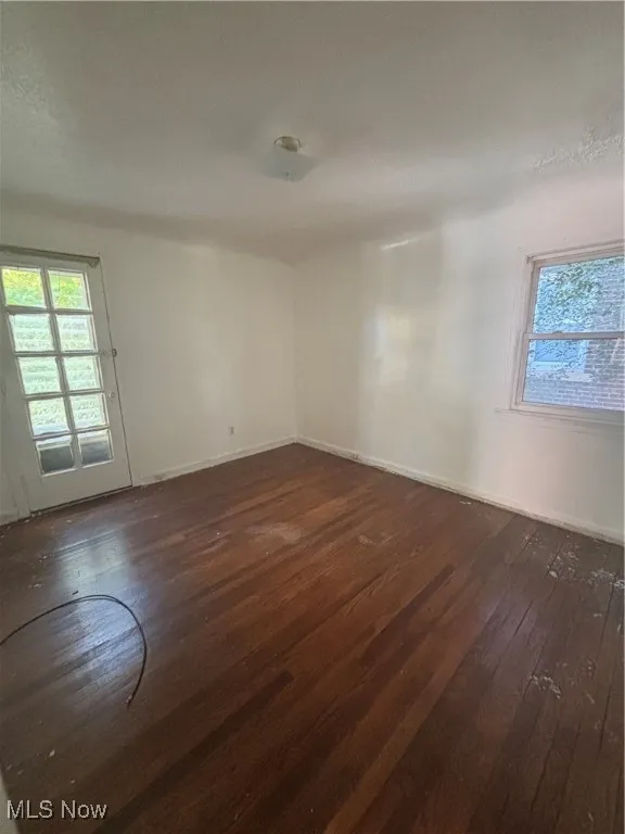 Unfurnished room with dark wood finished floors and baseboards