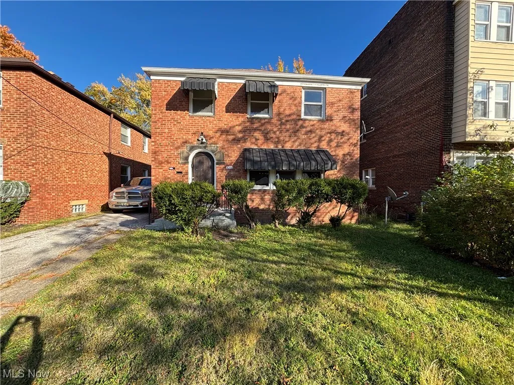 View of front of house featuring brick siding, a front yard, and driveway