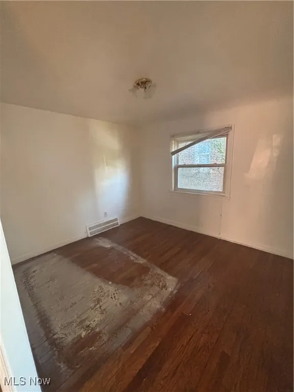 Unfurnished room with dark wood-style floors and baseboards