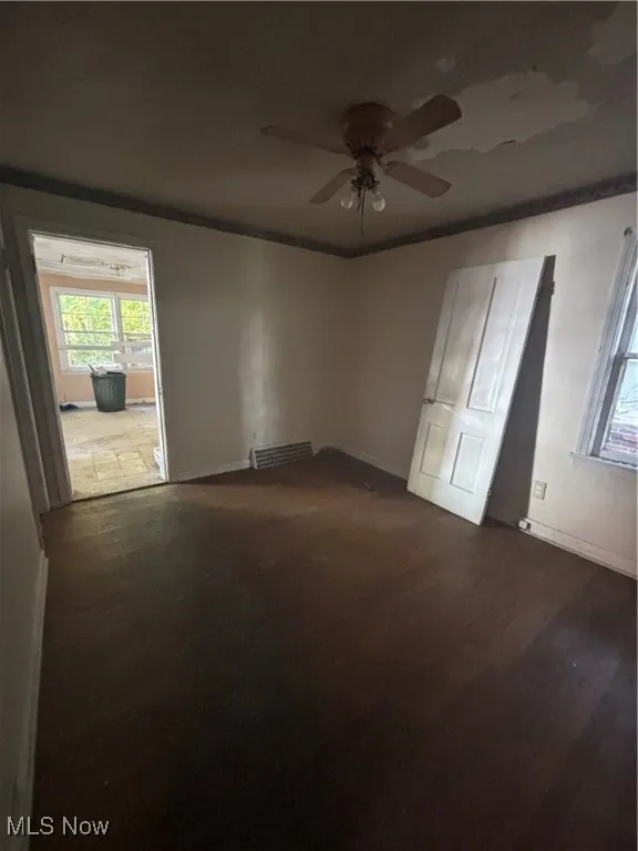 Unfurnished room with dark wood-type flooring, crown molding, and ceiling fan