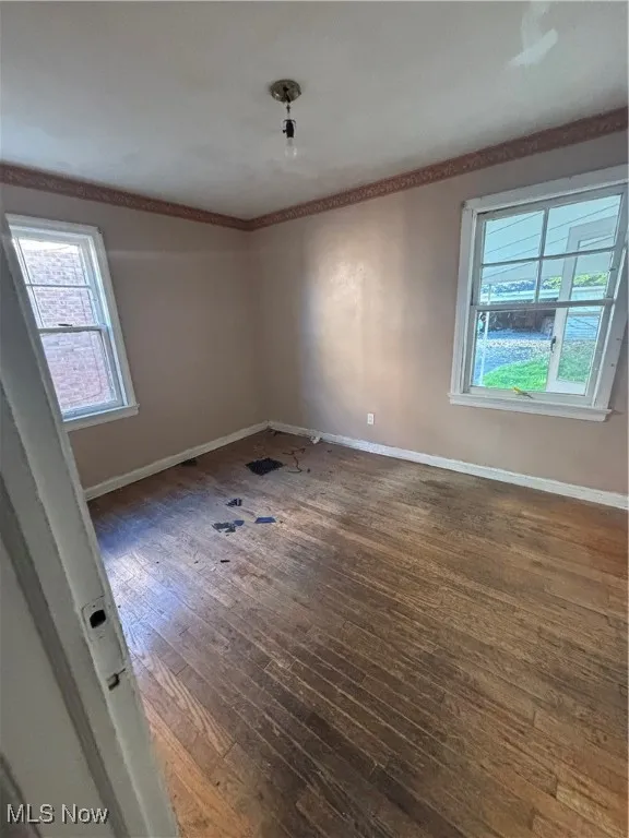 Spare room featuring dark wood finished floors and ornamental molding