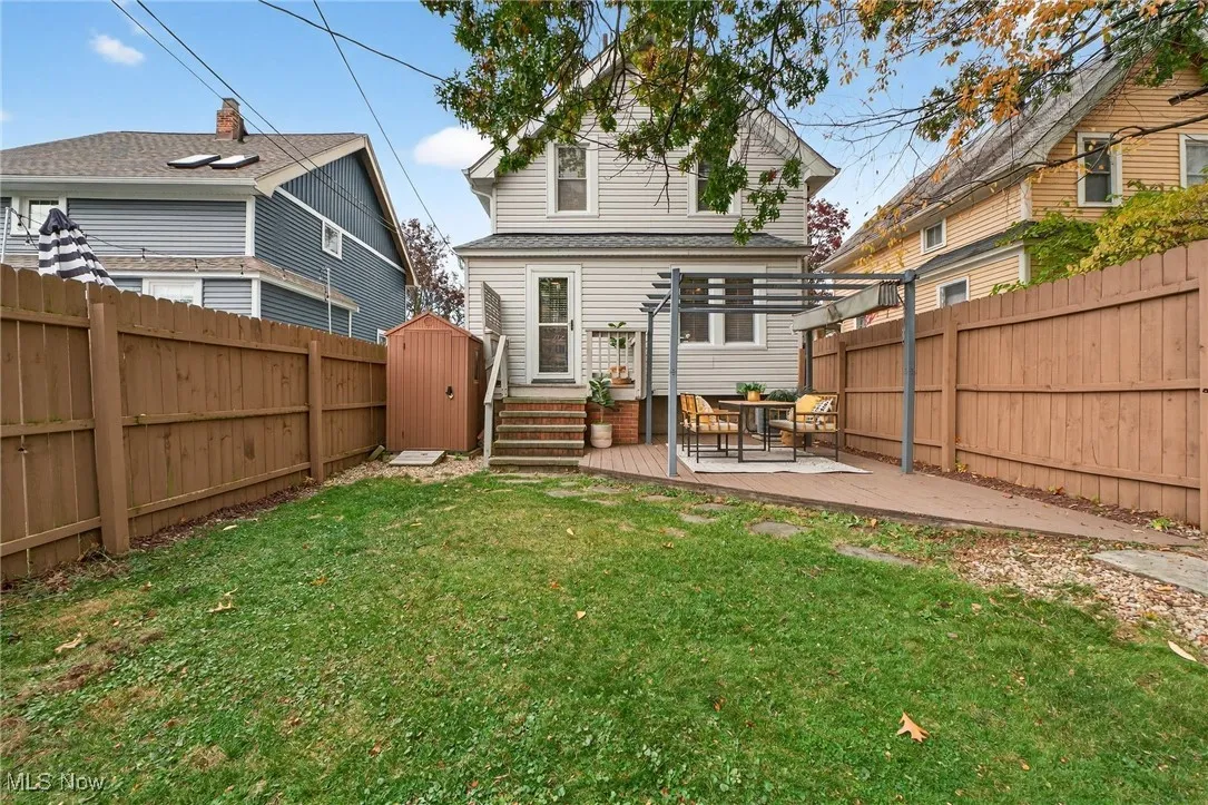 Rear view of house featuring a shed, a wooden deck, and a fenced backyard