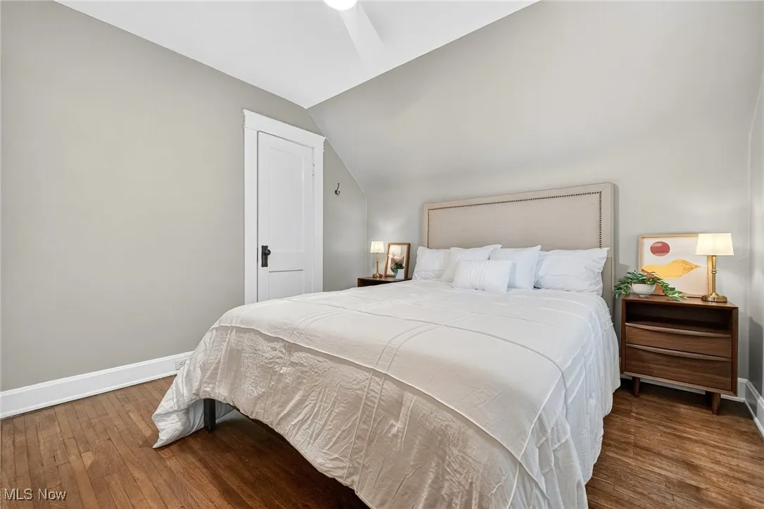Bedroom with dark wood-style floors, vaulted ceiling, and ceiling fan