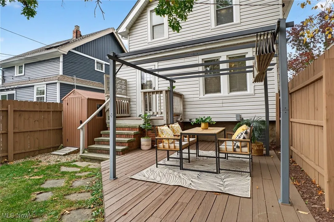 Back of house with a fenced backyard, a deck, a storage unit, and outdoor lounge area