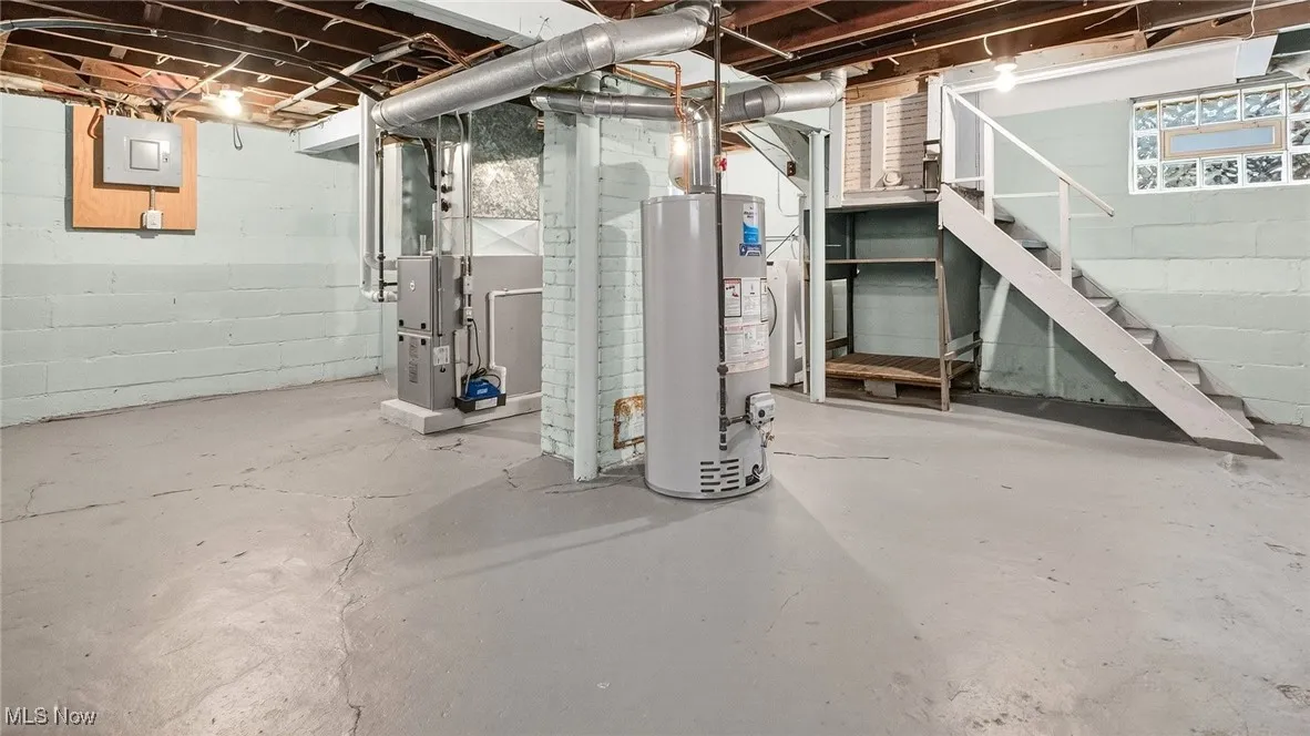 Basement featuring stairs, water heater, and heating unit