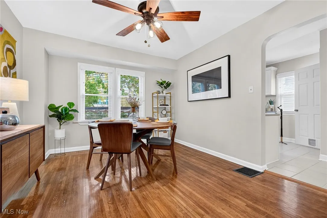 Dining area featuring dark wood-type flooring, a ceiling fan, and arched walkways