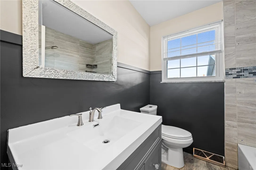 Full bath with vanity, tile walls, wood finished floors, and bathtub / shower combination