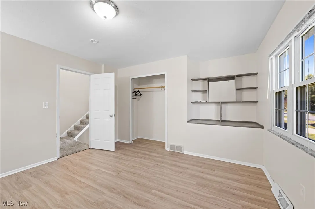 Bedroom with light wood-style flooring, a closet, and a baseboard radiator