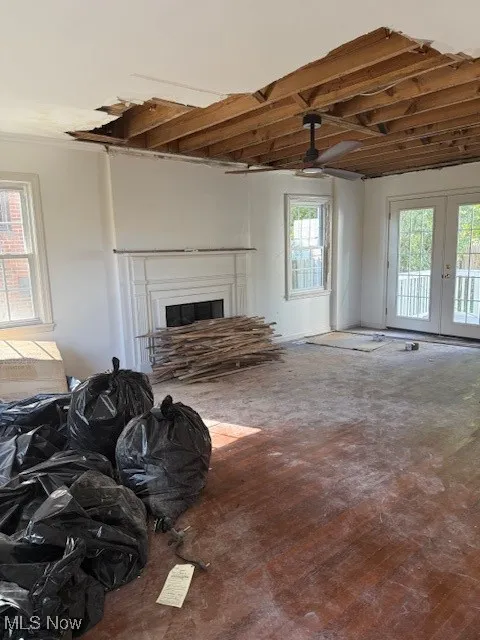 Unfurnished living room with a glass covered fireplace, french doors, and wood-type flooring