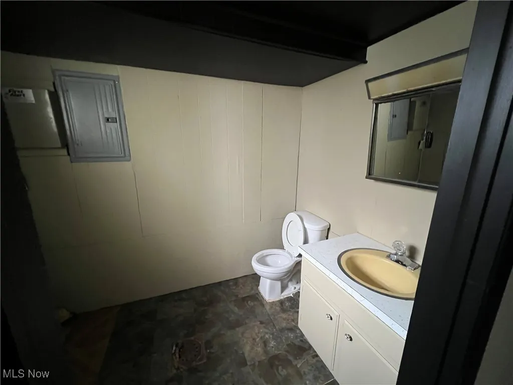 Bathroom with vanity, electric panel, and dark stone finish flooring