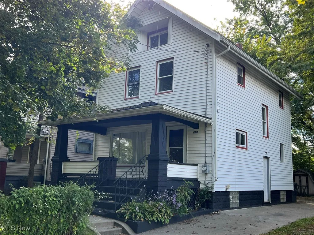 American foursquare style home with covered porch and an outdoor structure