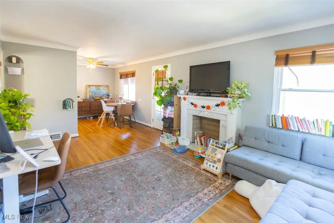 Down unit Living area with light wood-style floors, ceiling fan, and a high end fireplace