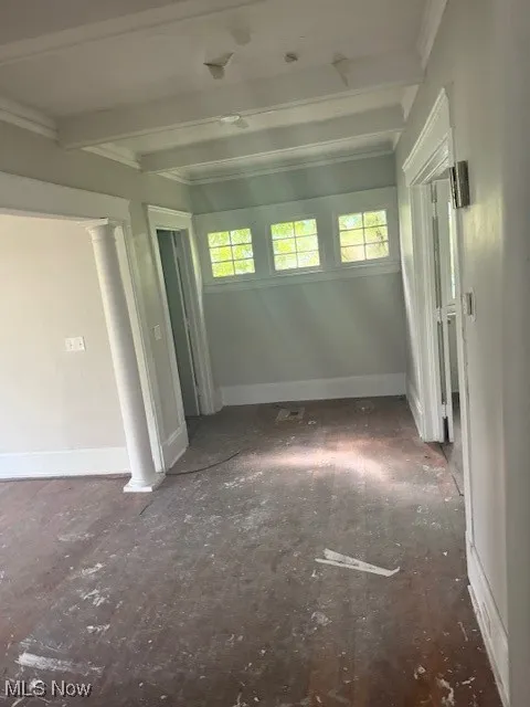 Unfurnished room featuring ornate columns, beam ceiling, and plenty of natural light
