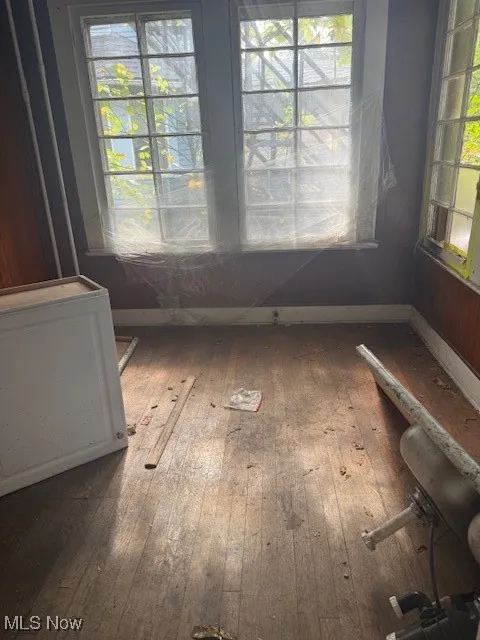 Unfurnished dining area with dark wood-style flooring and baseboards