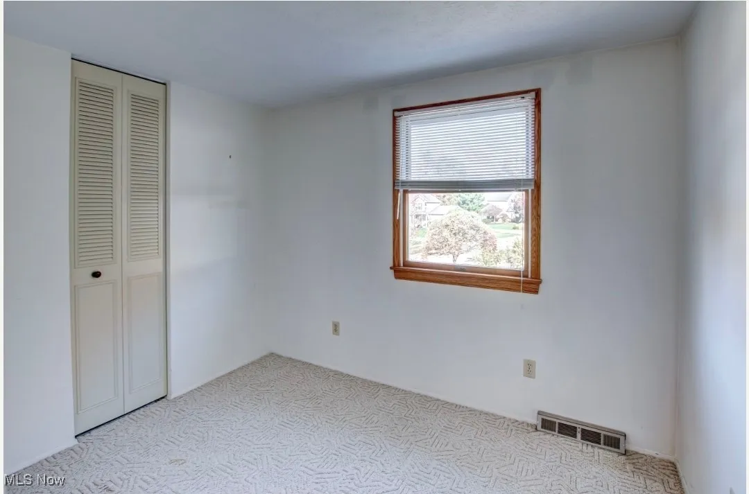 Unfurnished bedroom with light carpet and a closet