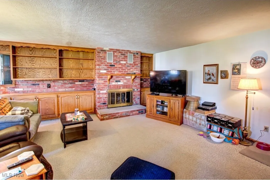 Living area featuring light colored carpet, a textured ceiling, and a fireplace