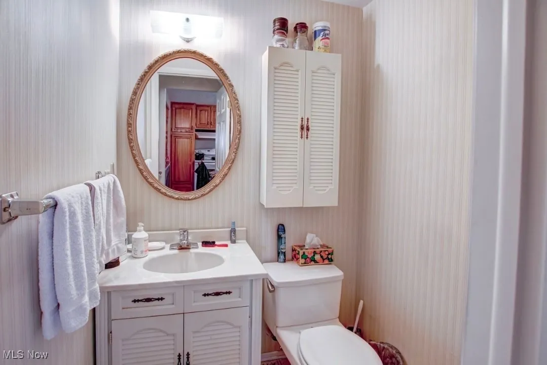 Half Bathroom with vanity, wallpapered walls on first floor