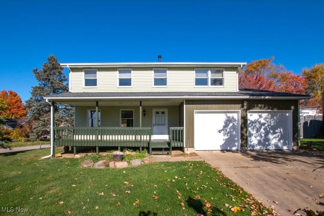 Traditional-style home with a porch, a garage, a front yard, and driveway