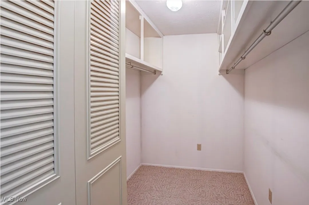 Master bedroom spacious walk in closet featuring light colored carpet