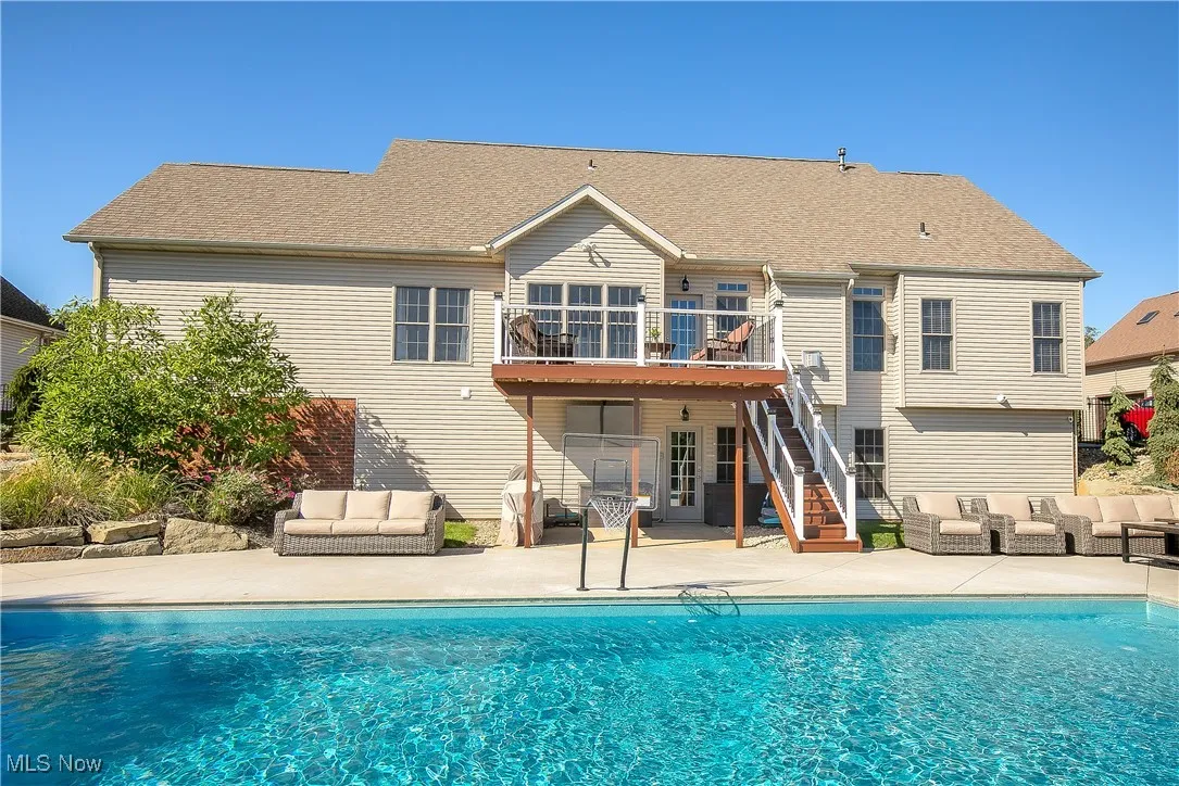 Back of property featuring outdoor lounge area, a patio area, stairway, and an outdoor pool