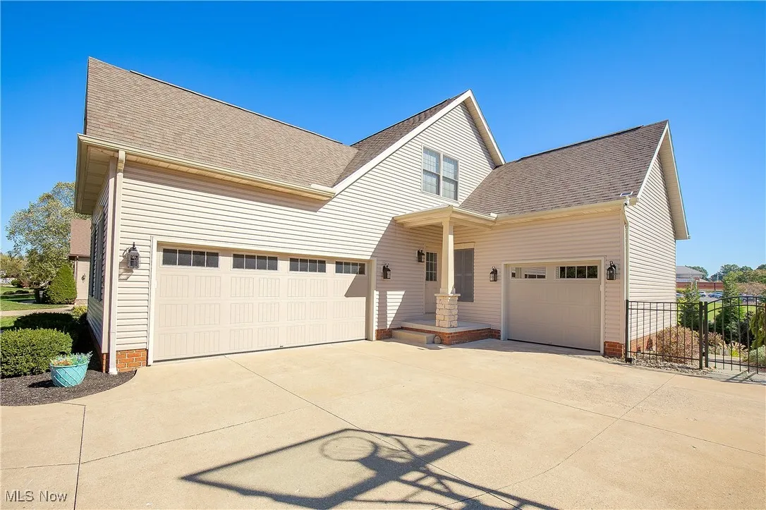 View of front facade with a shingled roof, concrete driveway, and a gate