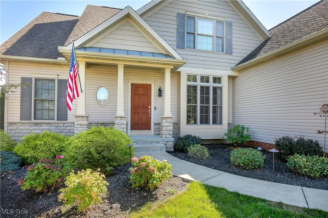 View of front facade featuring stone siding, roof with shingles, and a standing seam roof