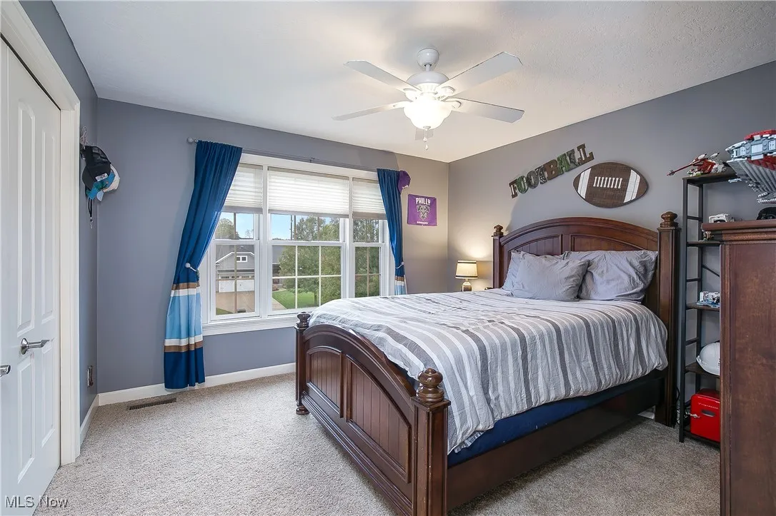 Bedroom with light colored carpet, a closet, and a ceiling fan