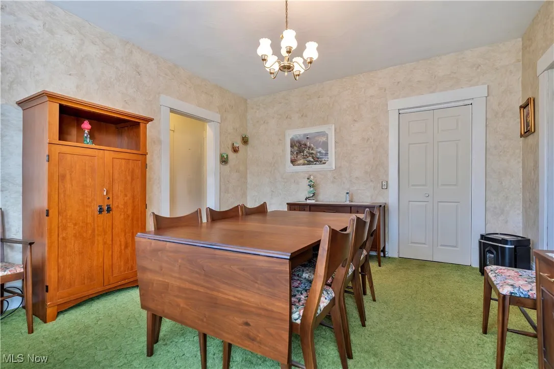 Dining area with light colored carpet and a chandelier