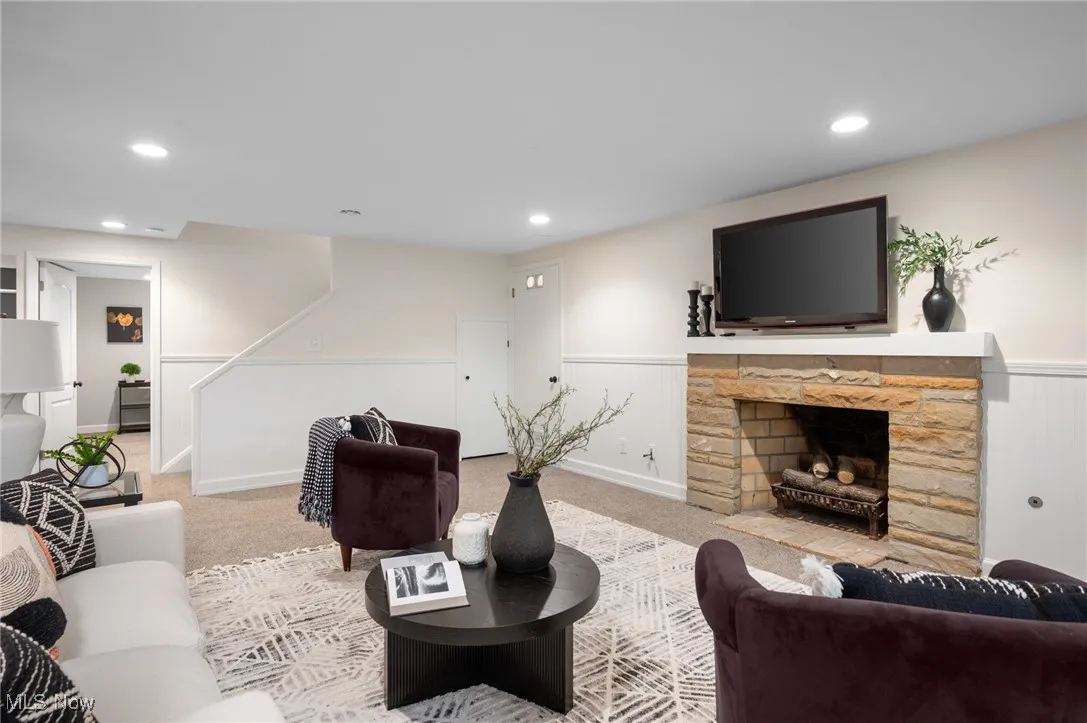 Another wood-burning fireplace with gas starter tops off the space alongside clean white wainscotting.