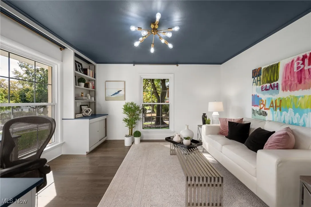 A sizable first floor office creates an impressive video call backdrop, with the chandelier, large built-ins and fun colored ceiling.