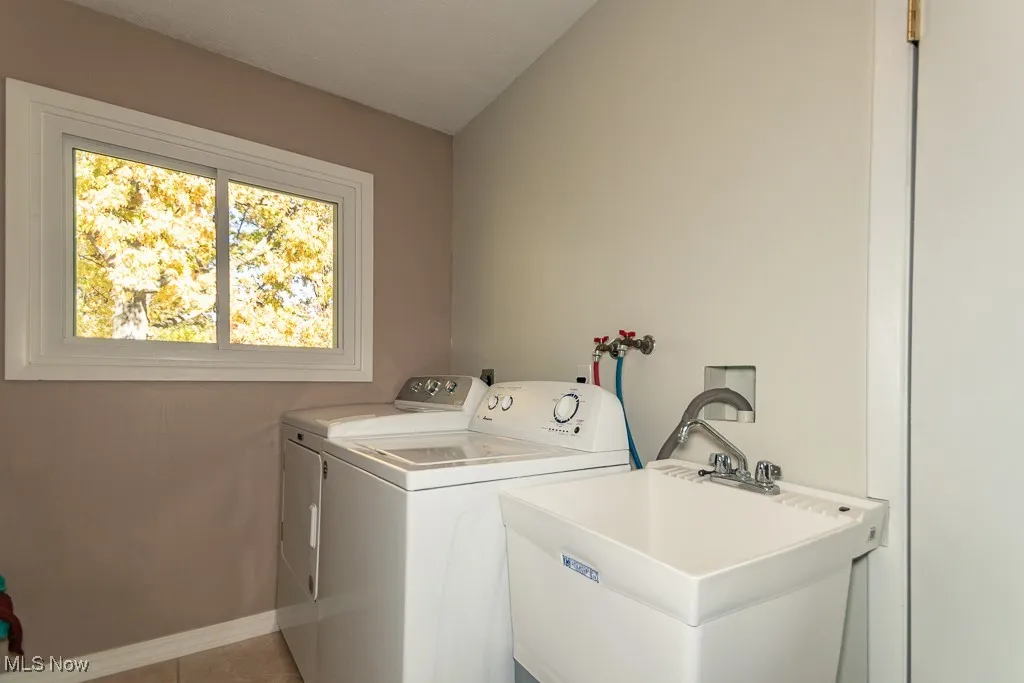 Washroom with independent washer and dryer, lofted ceiling, and light tile patterned flooring