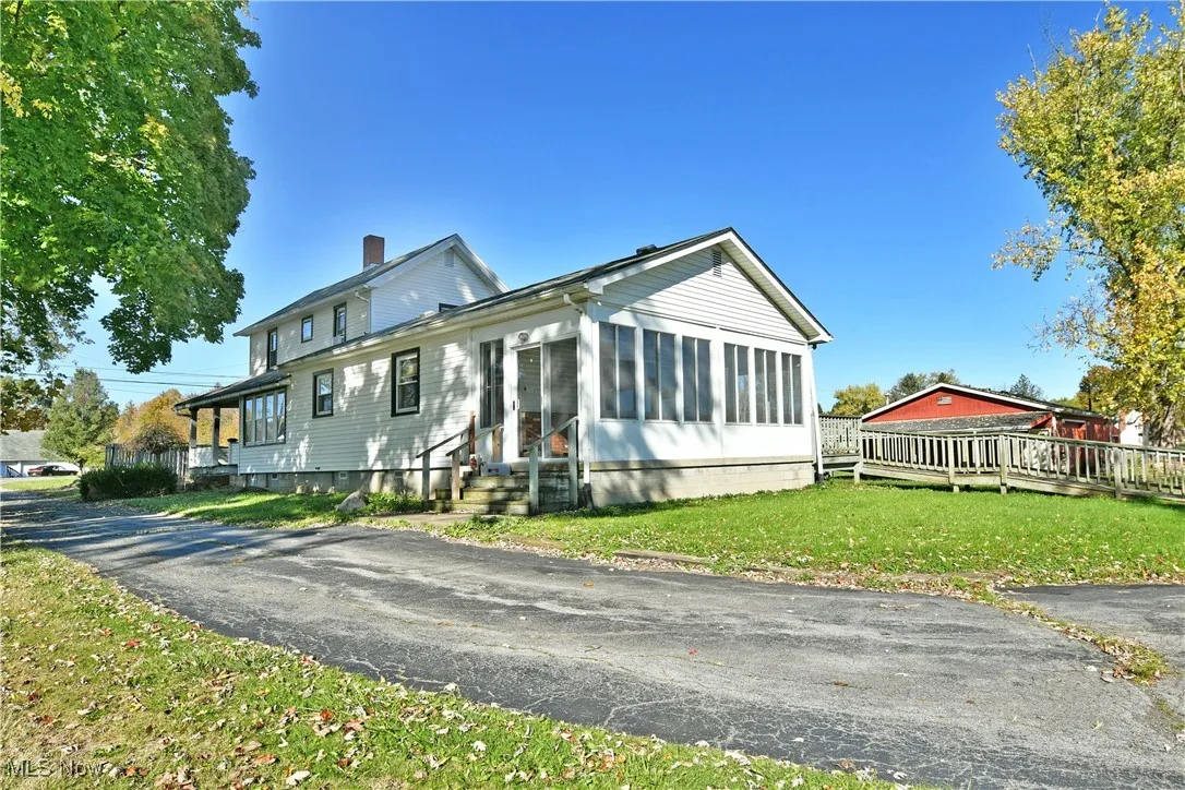 View of front facade with a sunroom, a front lawn, a chimney, and entry steps