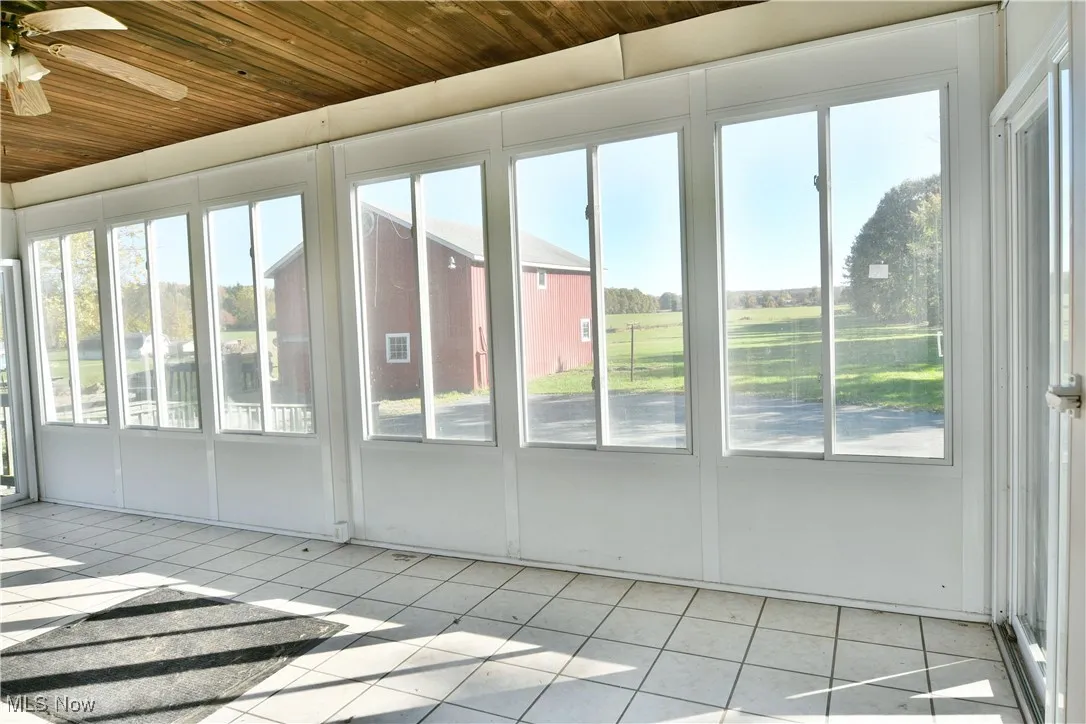 Unfurnished sunroom with healthy amount of natural light and ceiling fan