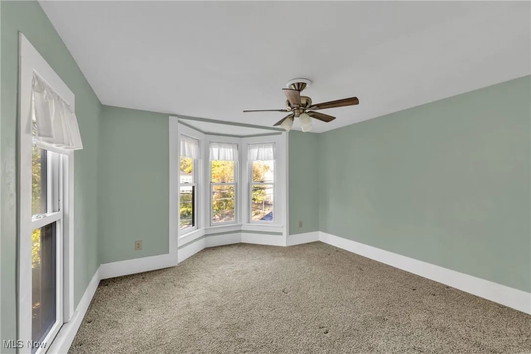 Empty room with light carpet and a ceiling fan