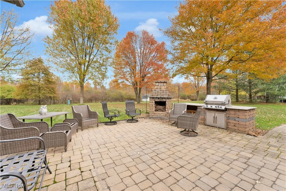 View of patio / terrace with an outdoor stone fireplace and area for grilling